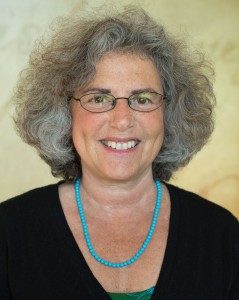 Headshot of woman with a blue necklace and a black top