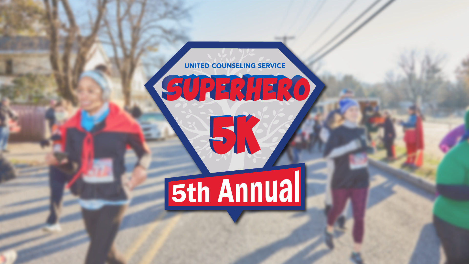 The Superhero 5K logo on top of a blurred picture of a group of people beginning a race wearing superhero outfits.