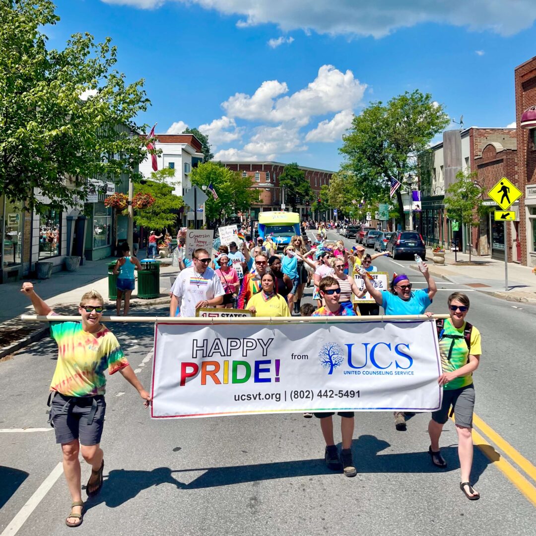 UCS employees participating in the Bennington Pride parade on Main Street in Bennington, VT holding a banner that says "Happy pride from UCS"