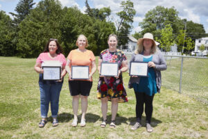 Four people pose for a group photo with awards.