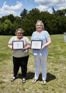 Two people pose for a photo while holding awards.