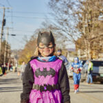 A young child with a pink batman costume smiles
