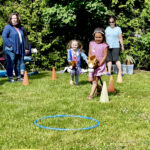 Two young children play with horse toys and navigate an obstacle course of hula hoops.