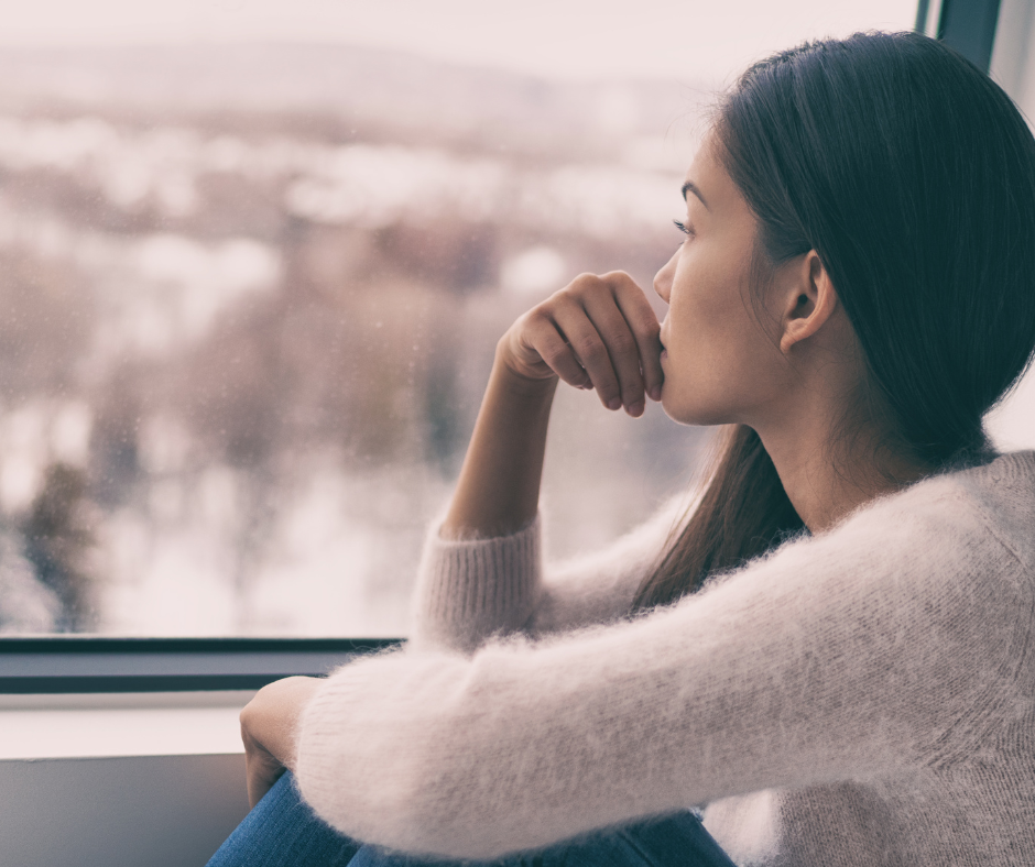A young women with long dark hair looking out the window.