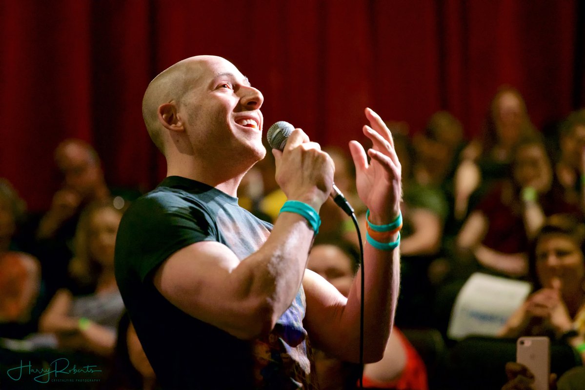 Man holding microphone speaking in front of a group of people