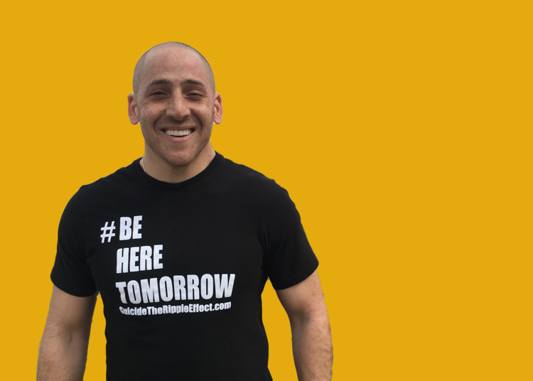 A man with a black t-shirt that reads "be here tomorrow" smiles and stands left of center against a yellow background.