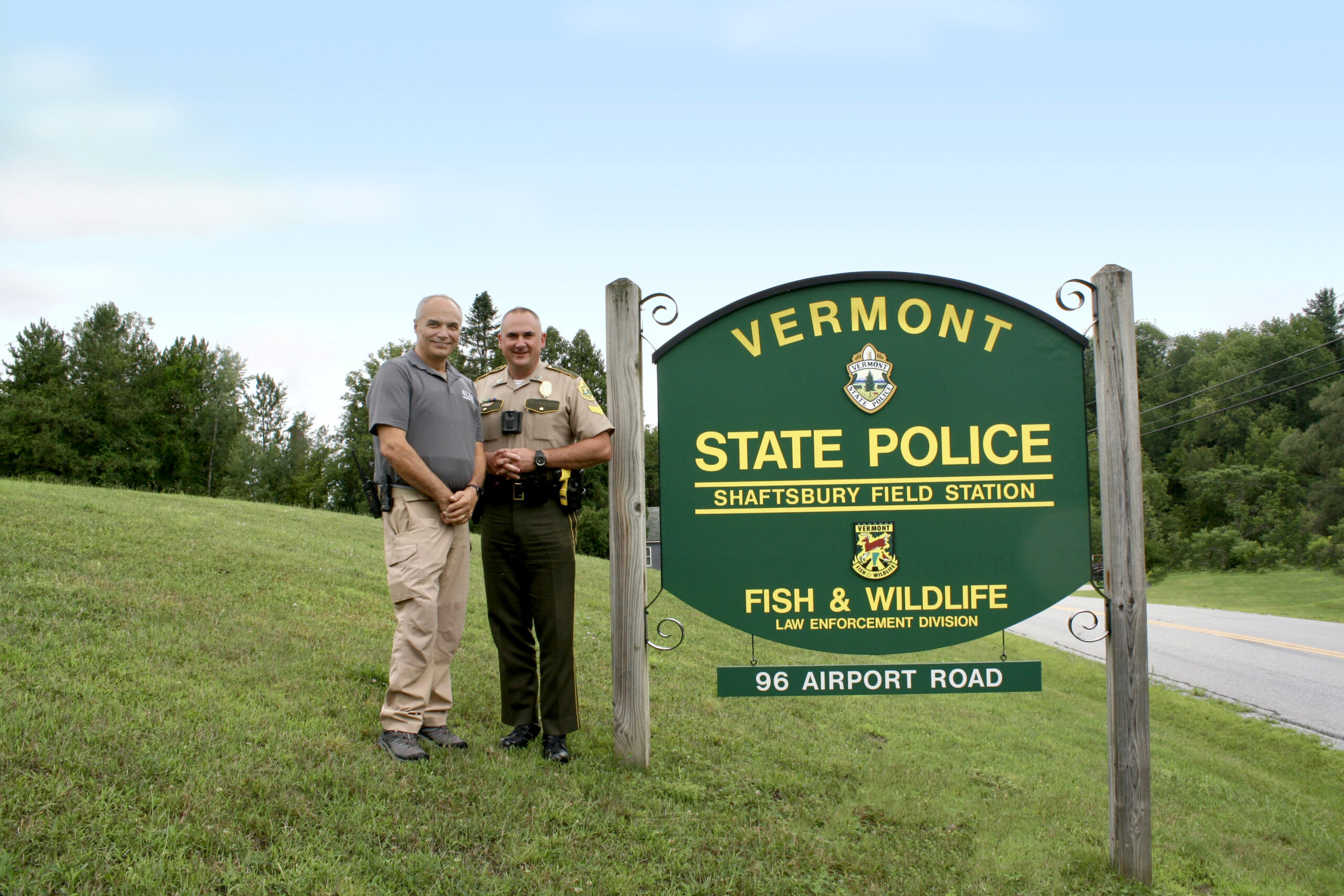 Two men standing outside next a sign that reads "Vermont State Police Shaftsbury Field Station"