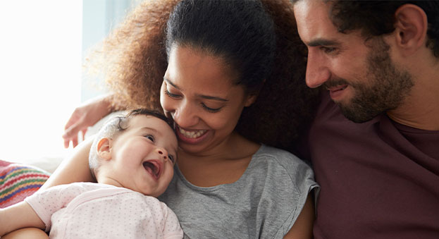 A smiling mother and father hold a laughing baby