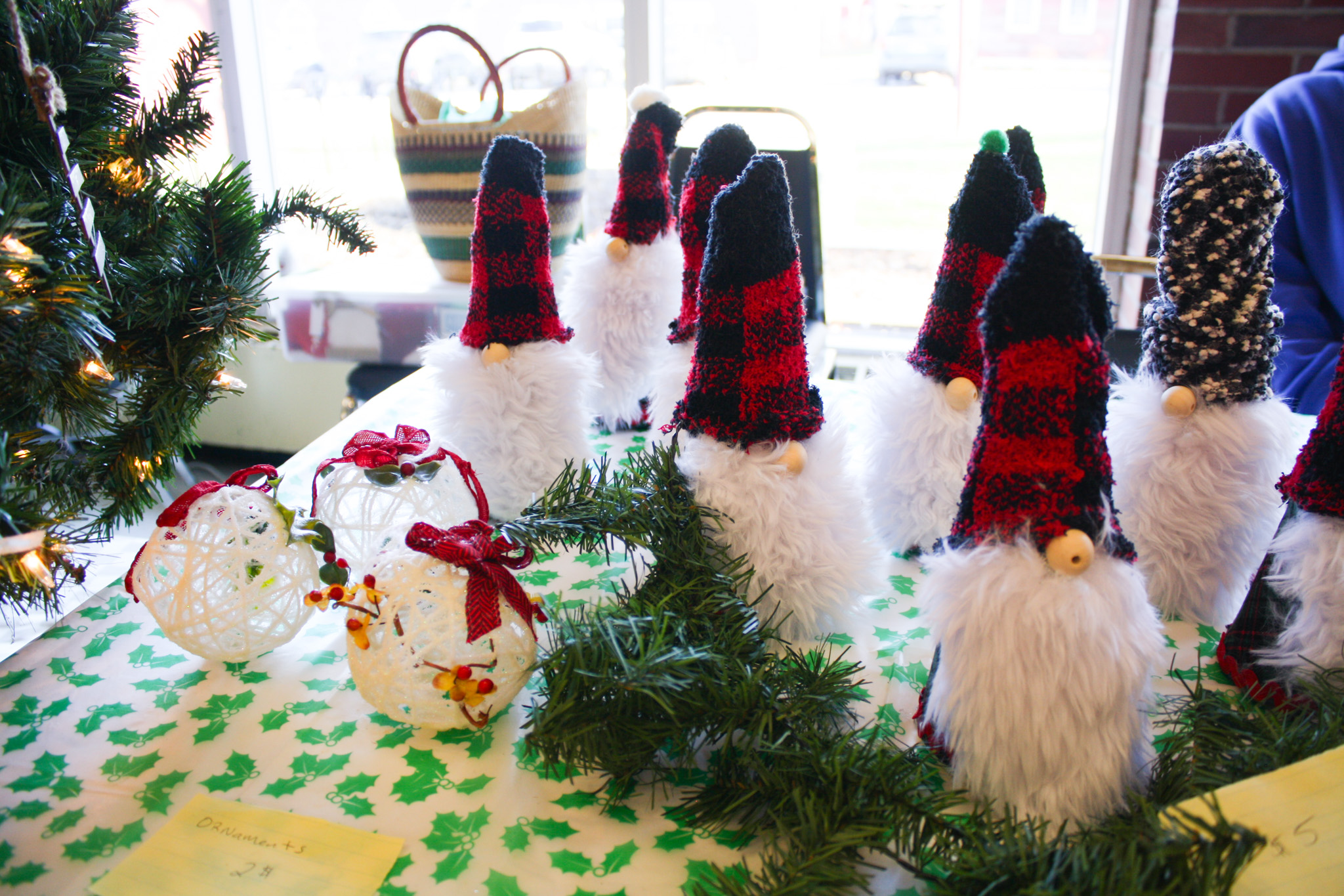 Several craft gnomes with fluffy white beards and tall hats stand among garland.
