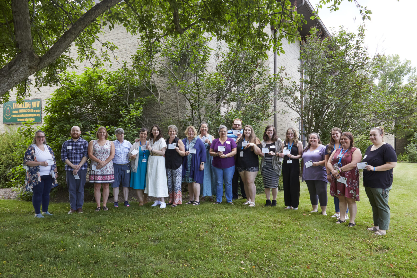 Group of people smiling outside holding cards