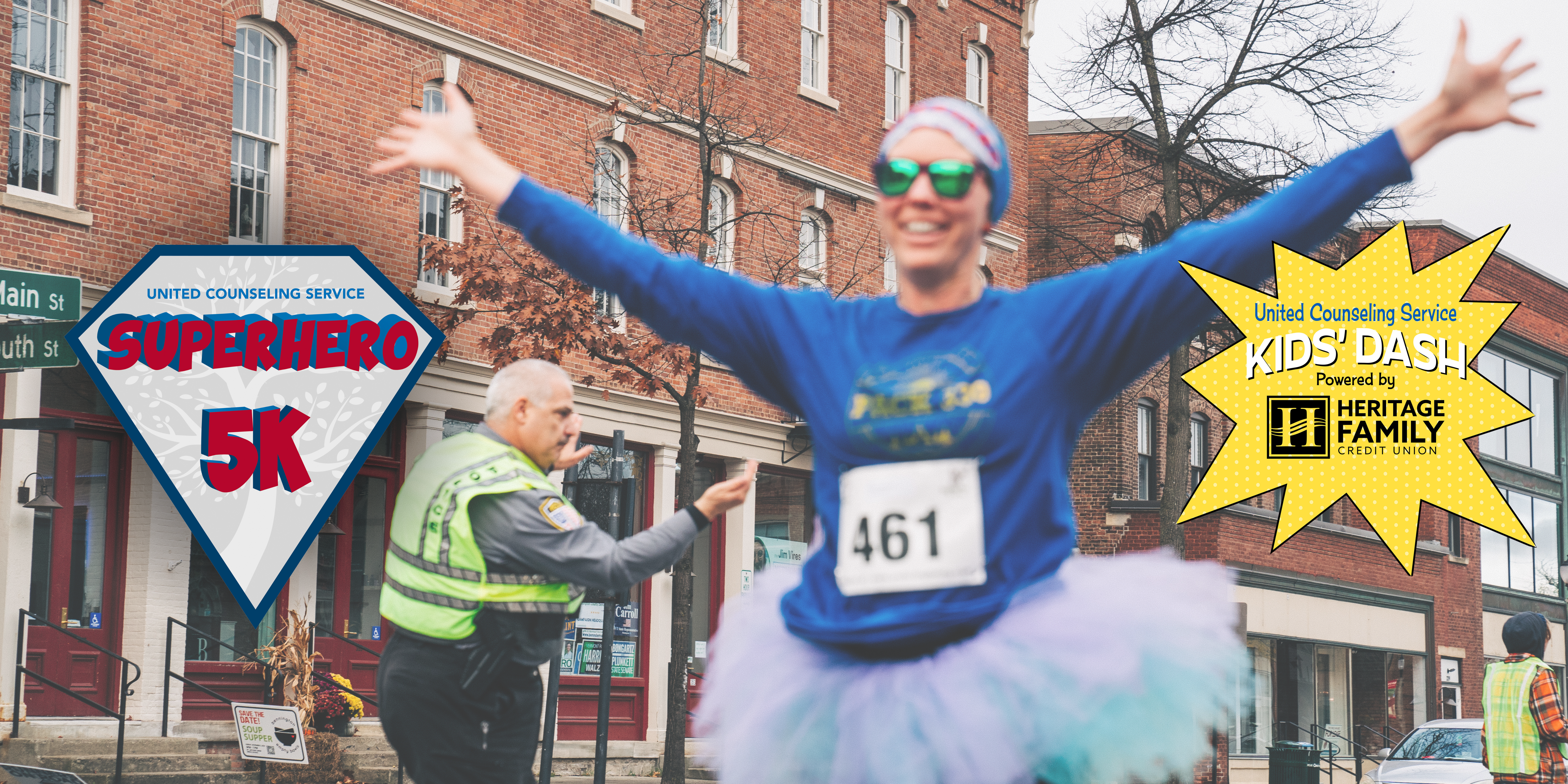 women in sunglass, long sleeve blue shirt and a blue and purple tutu is running with a smile and her arms in the air. Behind her is a police officer directing traffic