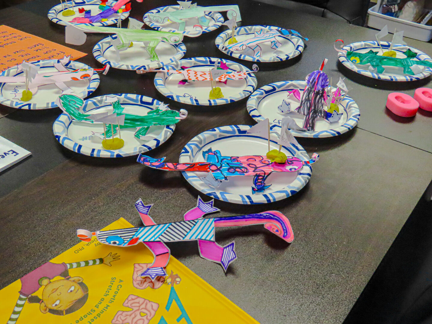 paper plates with brightly colored paper creatures on a brown table