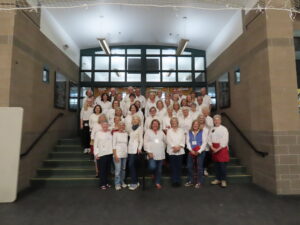Group of women and men in white shirts and dark pants stand together on steps.