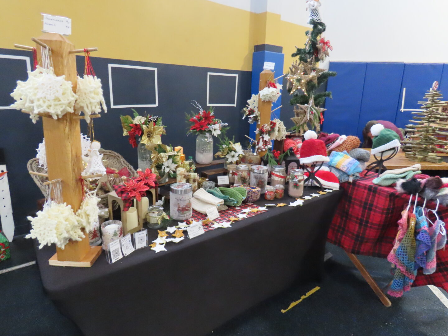 a table of craft fair items sits in a gym.