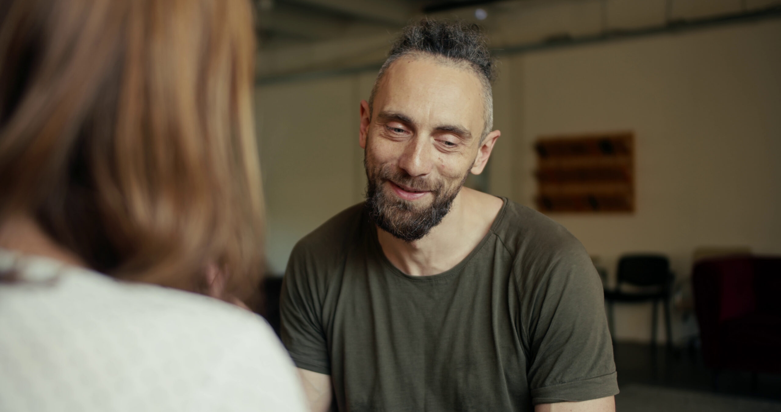 An adult man in a dark green shirt talking