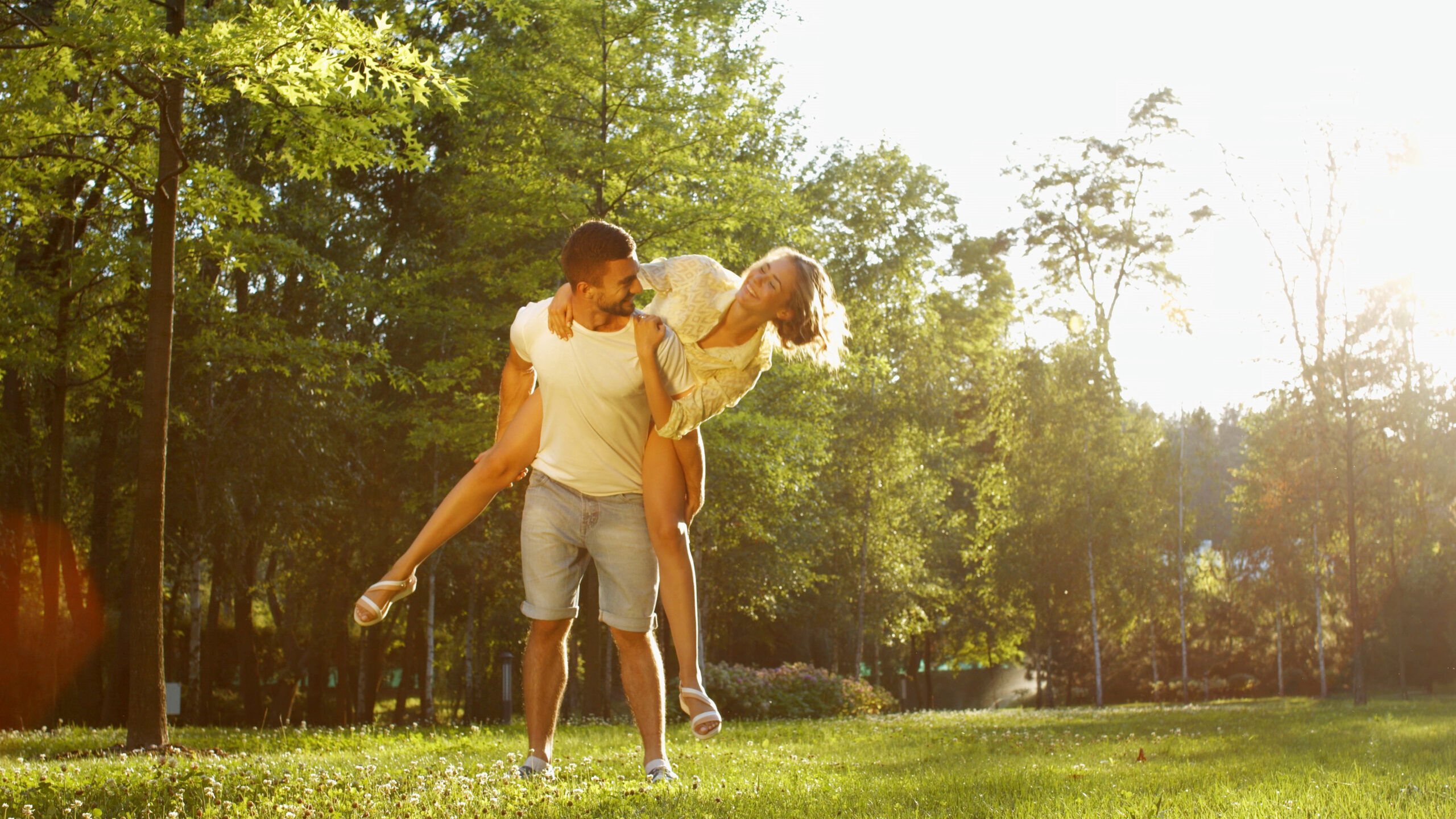 Guy carrying woman on his back smiling in a park