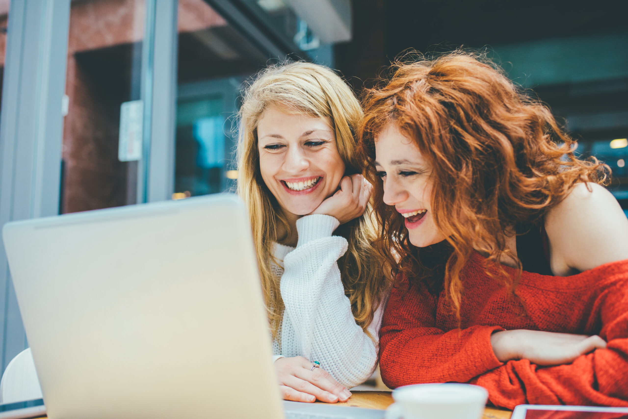 Two women using computer looking at the screen smiling
