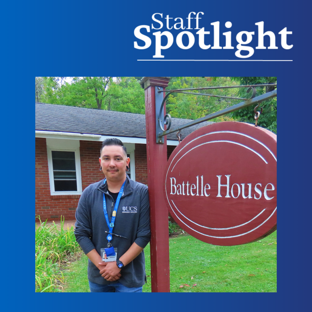 Staff Spotlight graphic featuring a UCS Emergency Services staff member standing beside a “Battelle House” sign outside a brick building, surrounded by trees and greenery.